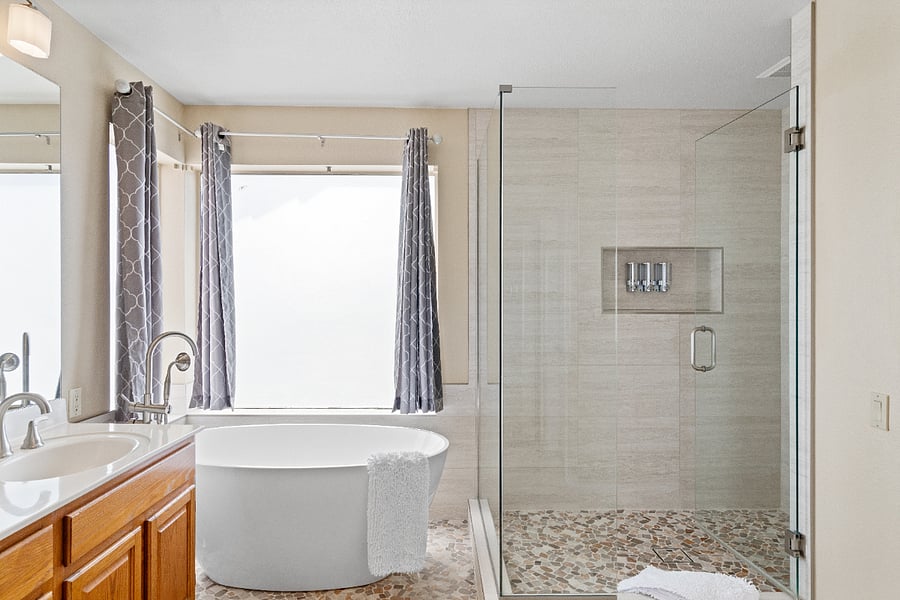The master bathroom upstairs features a separate bathtub and walk-in shower, along with a vanity and all the essentials needed for a comfortable stay.