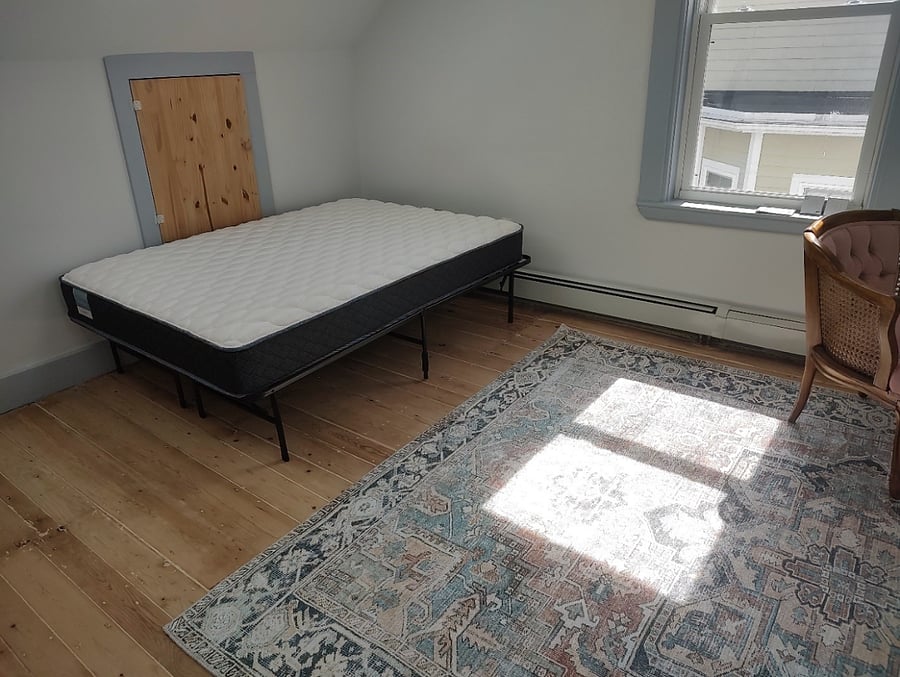 Third floor bedroom has a full bed and a rug.