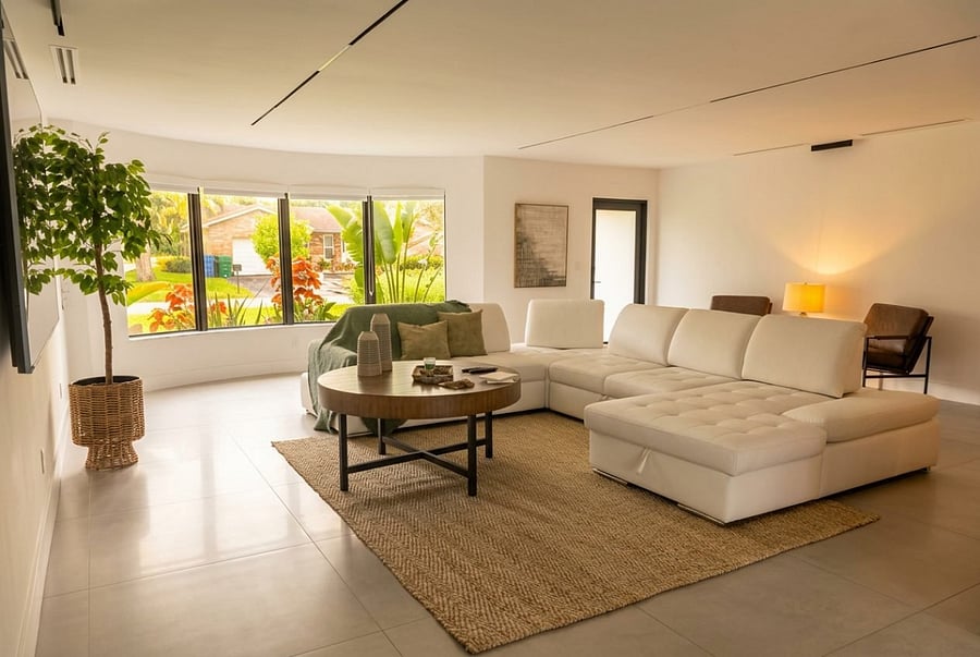 The living room offers a bright and inviting space with comfortable seating, large windows, and warm natural accents, creating the perfect place to relax and enjoy time together during your Coral Springs stay.