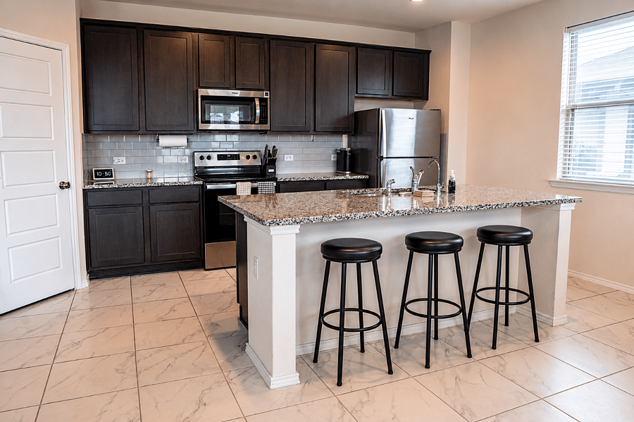 Fully furnished kitchen featuring a range, dishwasher, refrigerator/freezer, Keurig coffee maker, cookware, and all essential kitchen utensils.
