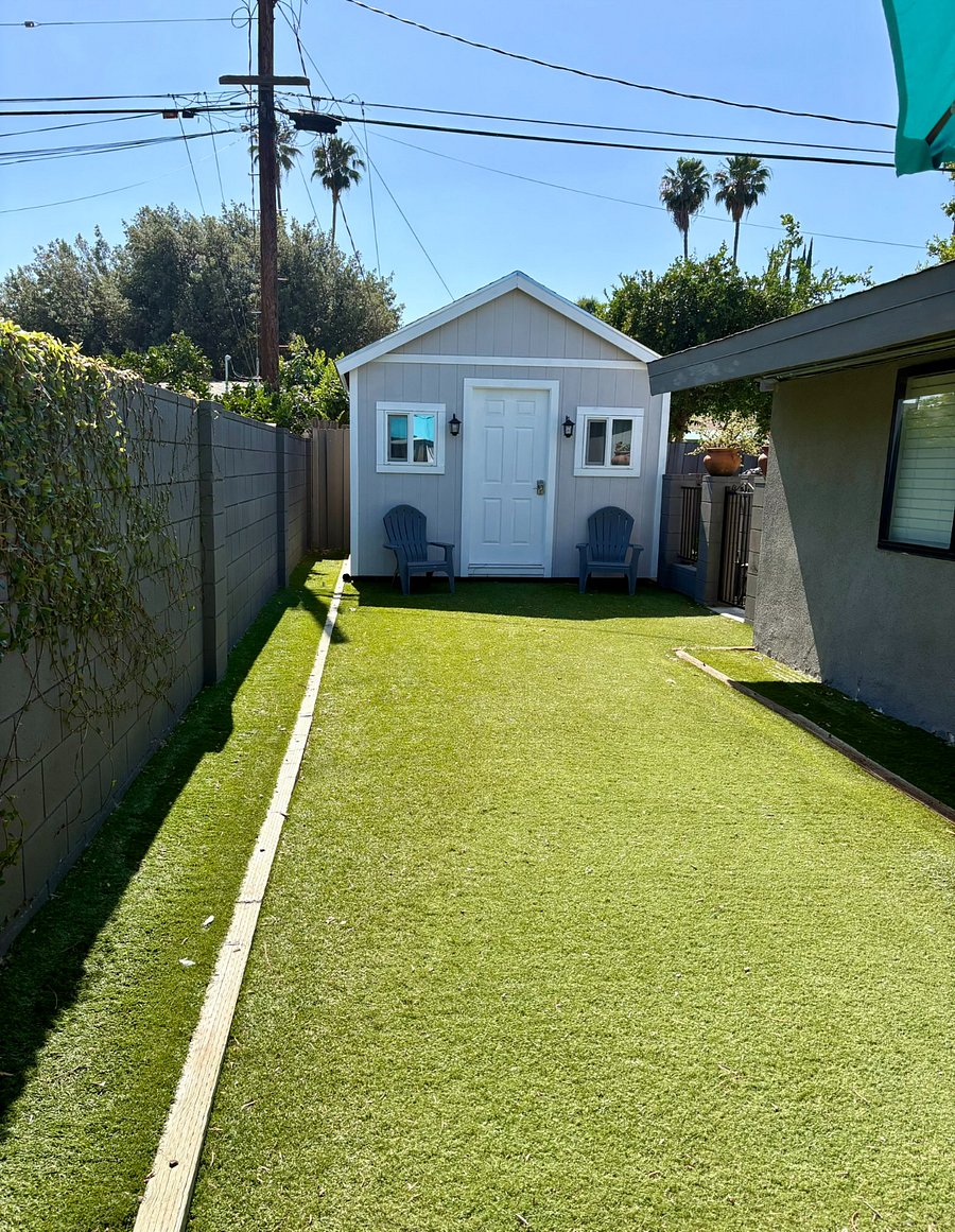 Lush artificial turf and Adirondack chairs set in front of a She-Shed. A quiet, private retreat separate from the pool area. (There is no access to the interior of the shed. Used for owner's storage.)