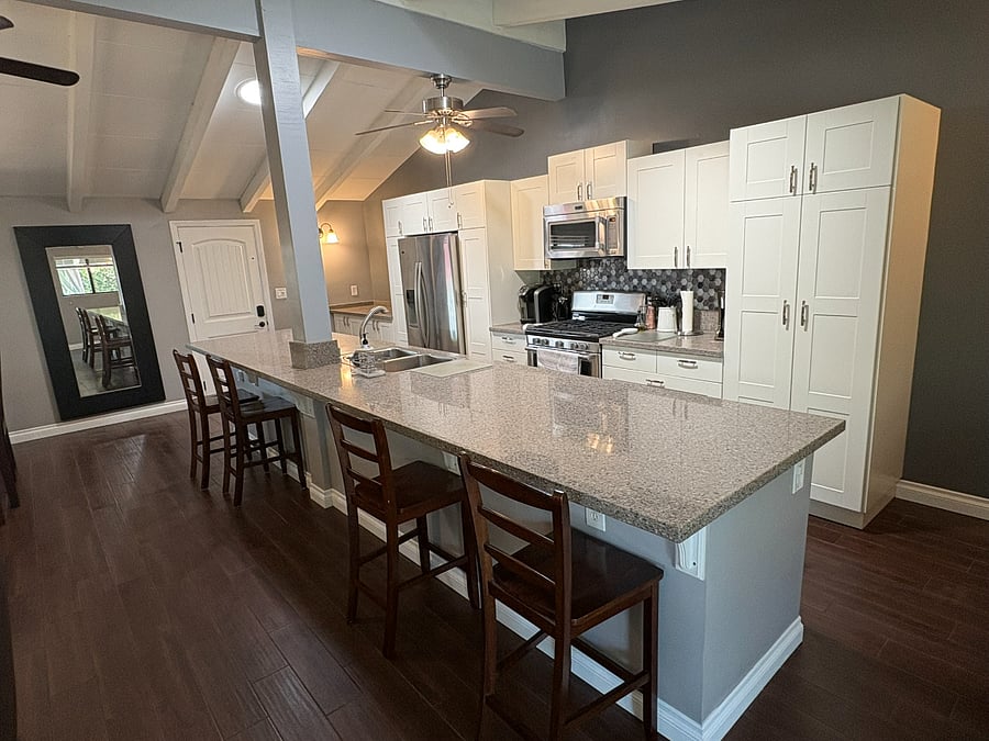 White shaker cabinets, quartz countertops, hex tile backsplash, stainless steel appliances and an expansive island with bar stools. Fully stocked and ready for cooking.