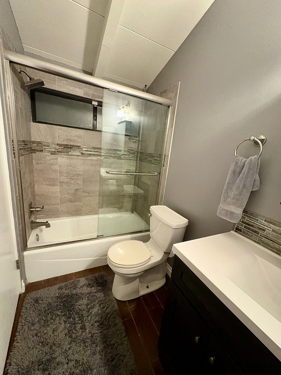 Primary bathroom has a glass-enclosed tub and shower with designer tile and fresh linens that are always stocked.
