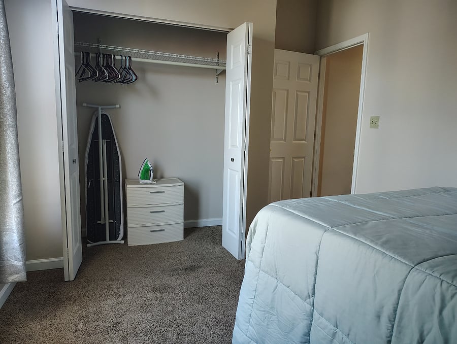 Guest bed closet includes iron board and chest of drawers
