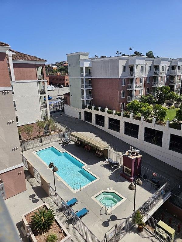 View of pool, hot tub, fireplace, grill from balcony