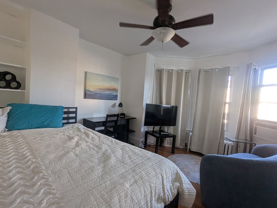 Front bedroom (Single Deluxe) - Twin XL or King bed (shown), hardwood floors, desk & chair workstation,  2 large closets with dresser and built-in storage shelves. This deluxe room also includes a private sitting area with loveseat sofa, TV and side table.