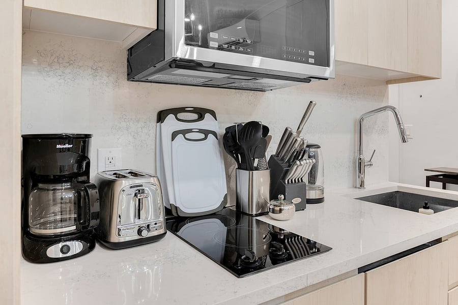 Modern kitchen with electric cooktop, toaster, and knife block  fully equipped to cook at home.