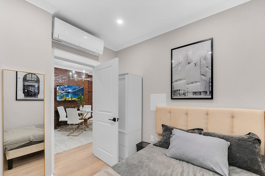 Bedroom with ductless A/C + heat, smart TV, and curated art.