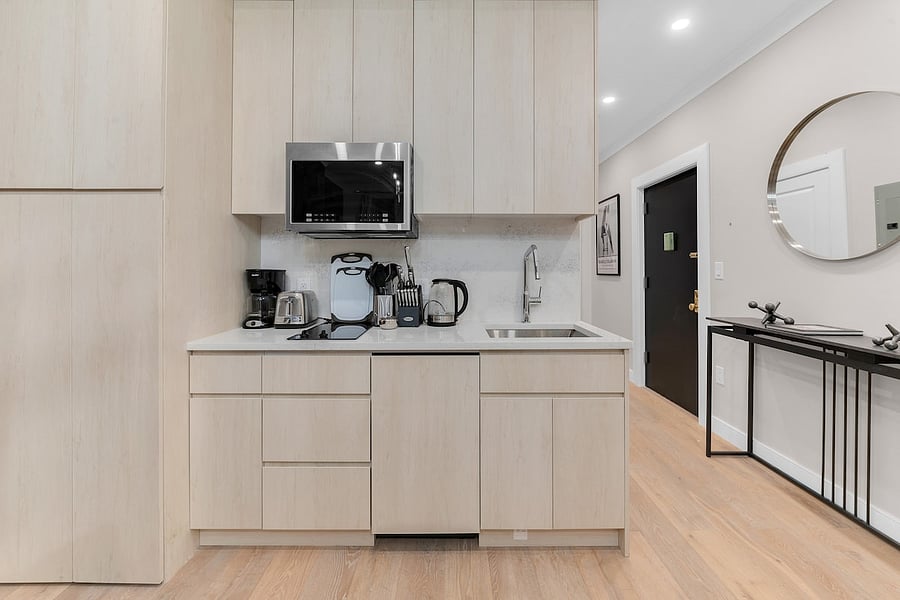 Second kitchen wall with microwave, sink, coffee maker, and kettle.