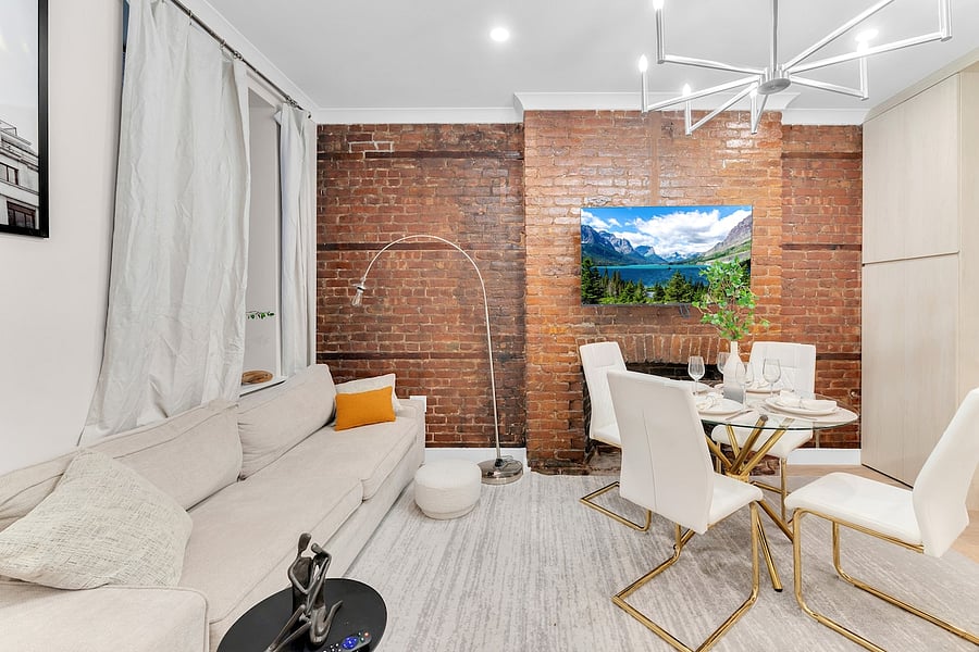 Exposed-brick lounge with smart TV, arc lamp, and dining for four.