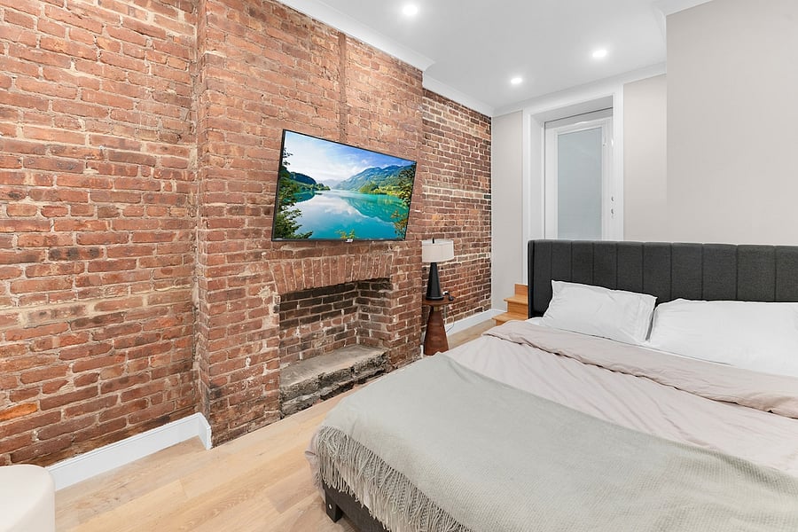 Bedroom with original exposed brick, decorative fireplace, and smart TV.