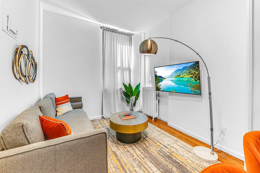 Cozy lounge with smart TV, curtains, and warm natural light.