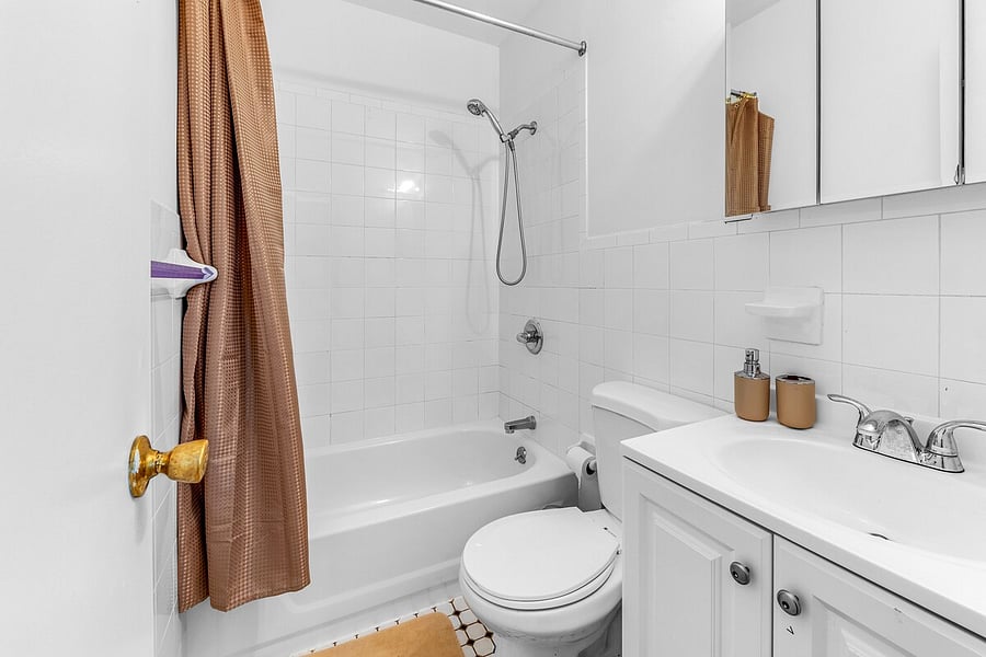 Clean full bathroom with tub-shower and vanity storage.