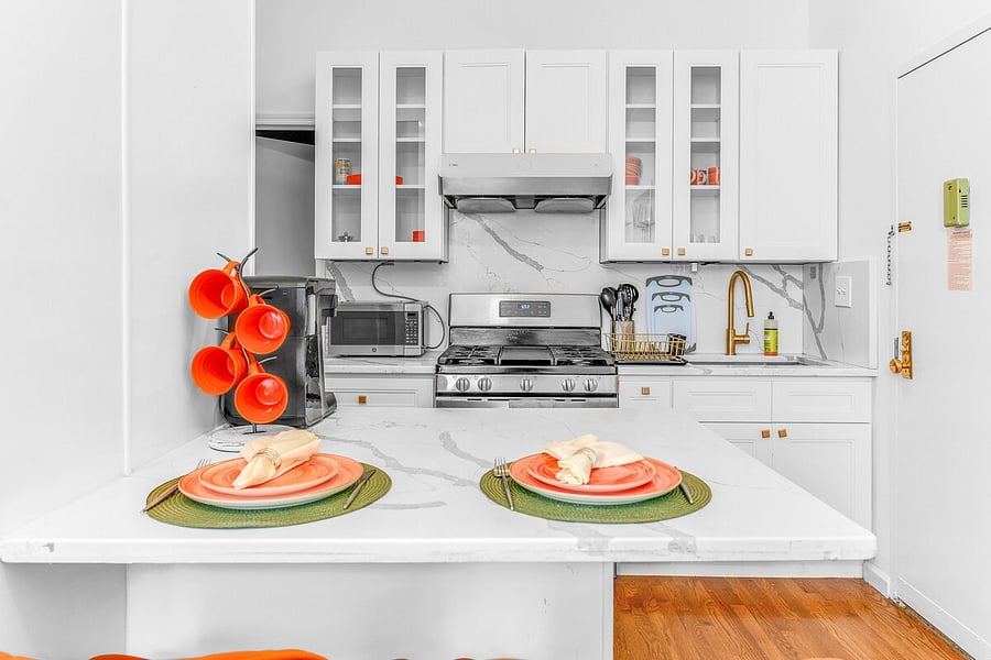 Sleek kitchen detail  stainless gas range, microwave, and quartz counters.
