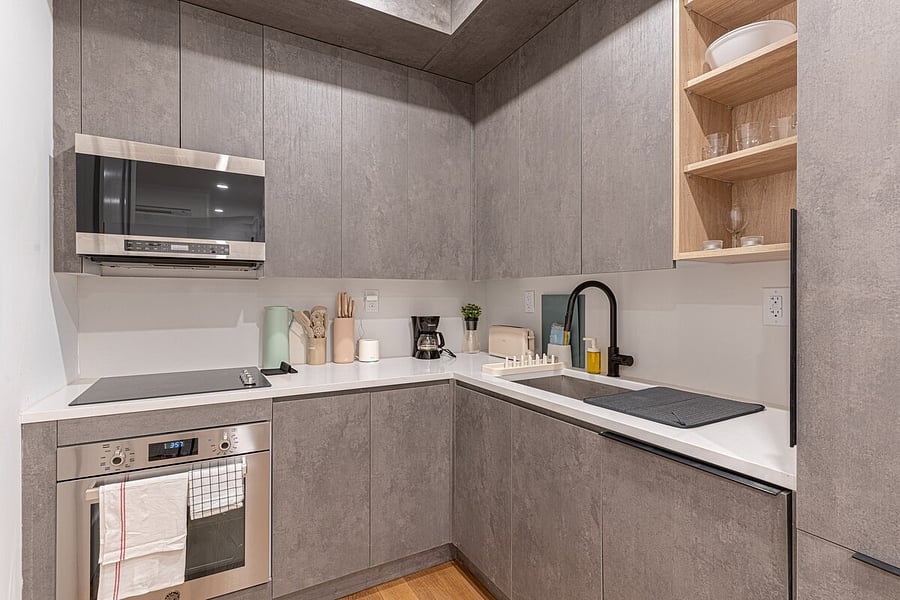 Fully equipped kitchen with stainless microwave, cooktop, sleek cabinetry and quartz counters  cook in and save while you explore Brooklyn.
