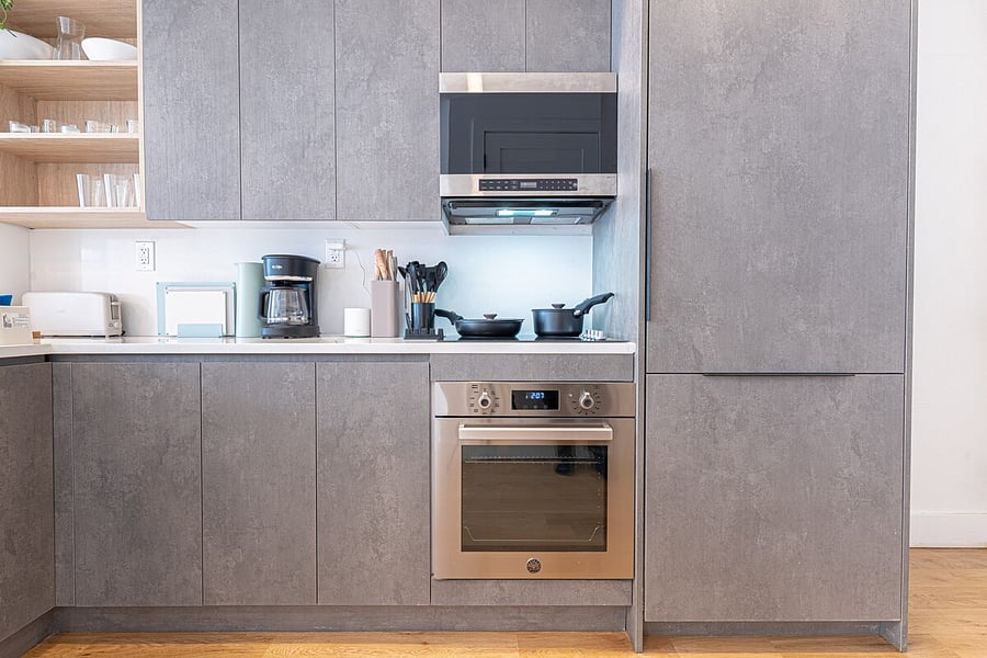 Sleek gray kitchen cabinetry with open shelving and built-in appliances  plenty of storage.