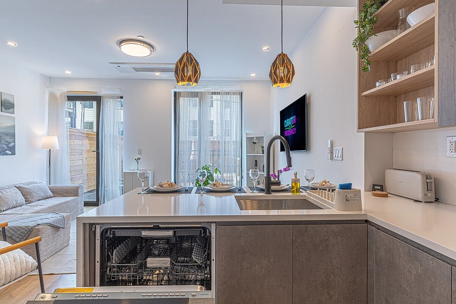 Open kitchen and living great room with an island, bar seating, and dishwasher.
