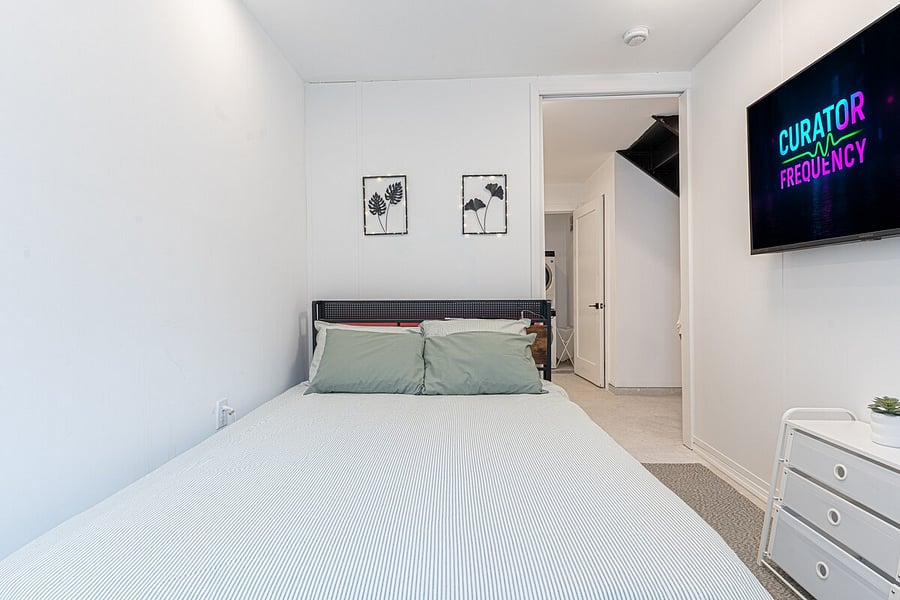 Light-filled bedroom with tall windows and cozy furnishings  wake up to plenty of sun.
