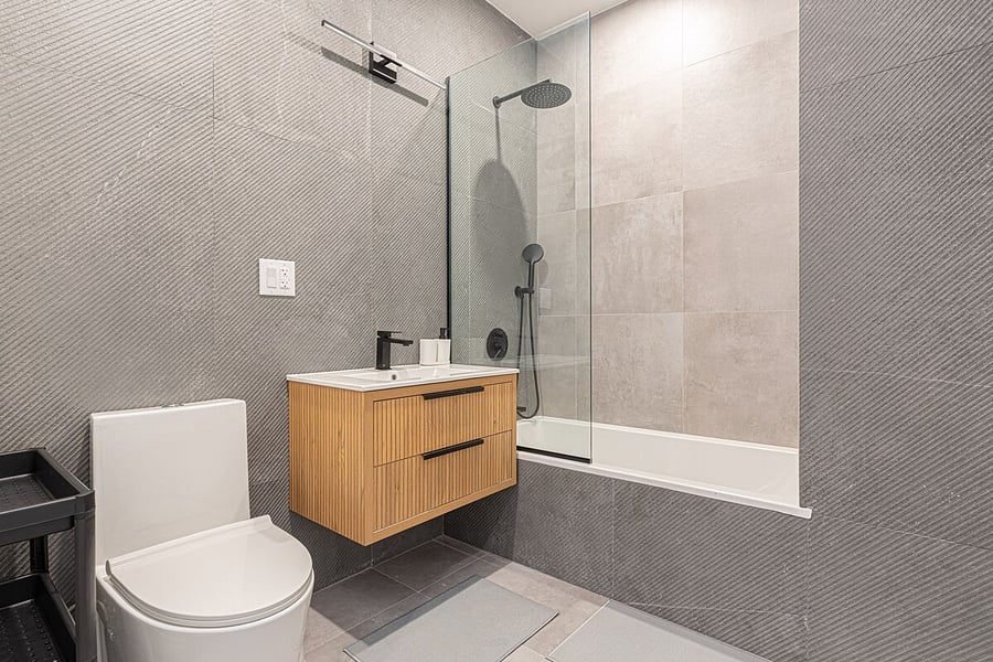 Modern full bath with a rainfall walk-in shower, floating wood vanity, and crisp tile.