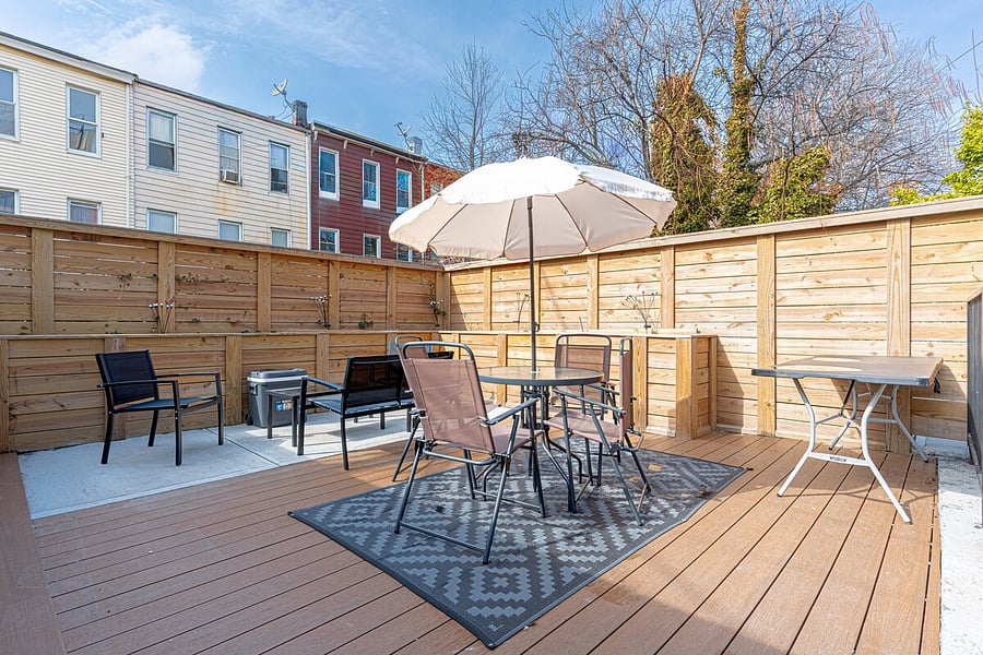 Spacious backyard deck with an umbrella dining set and grill  perfect for al fresco meals.