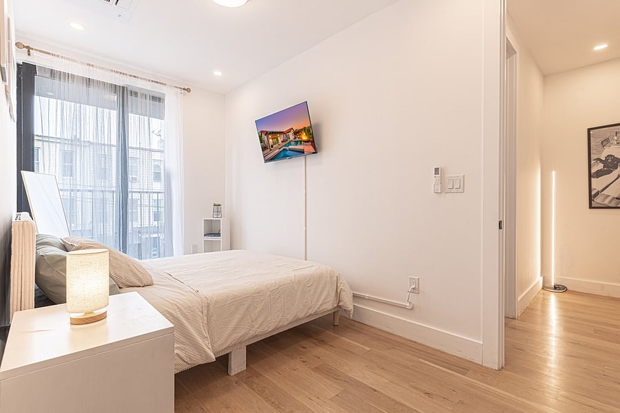 Bright, restful bedroom with big windows, a comfy bed and wall-mounted TV.