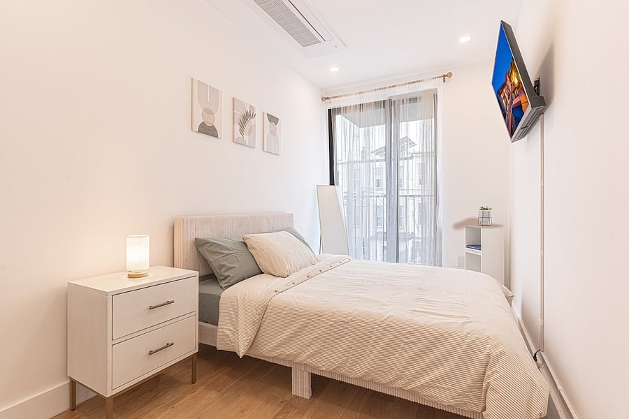 Serene bedroom with a comfortable bed, twin nightstands and a wall TV  rest easy.