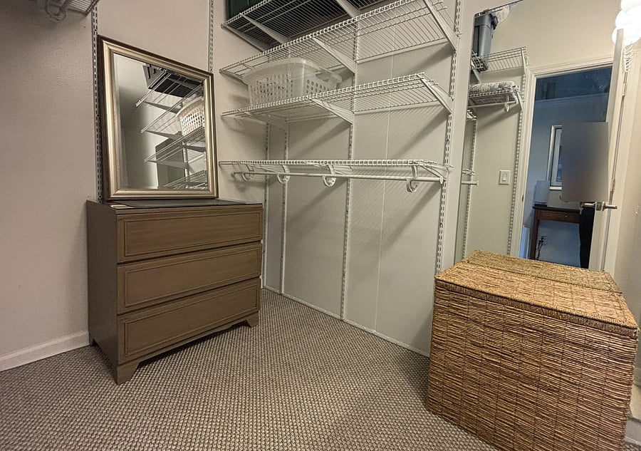 Large walk in closet with mirrors, hamper and dresser