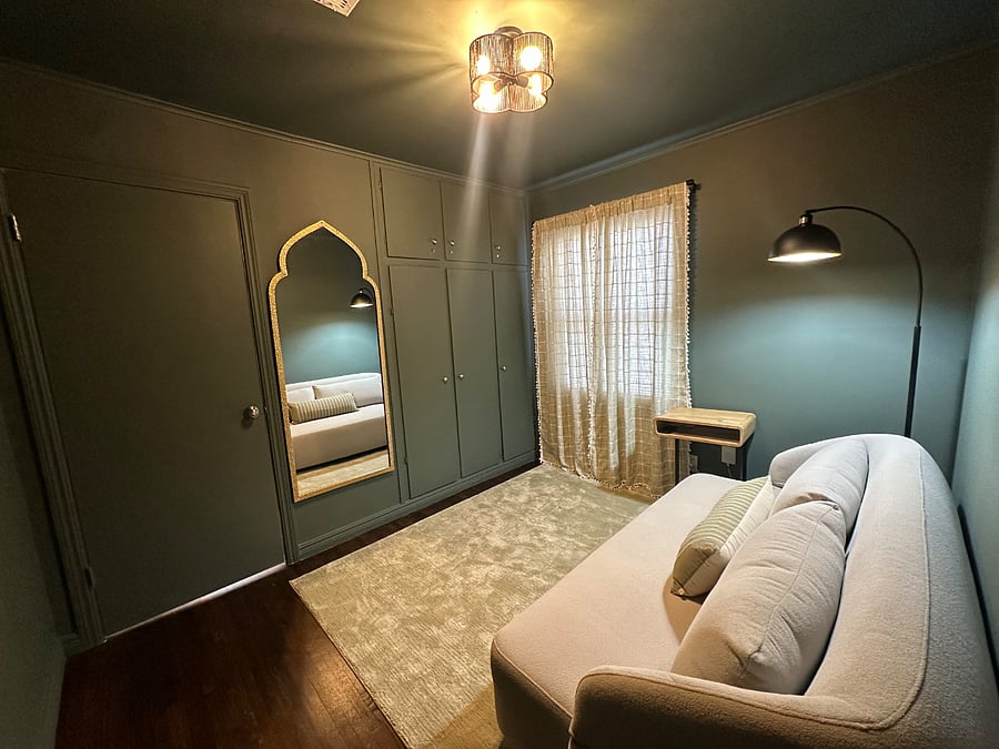This room has a cute little smart TV on the Left wall, a full-sized closet with hangers, extra bedding, and a big fan.