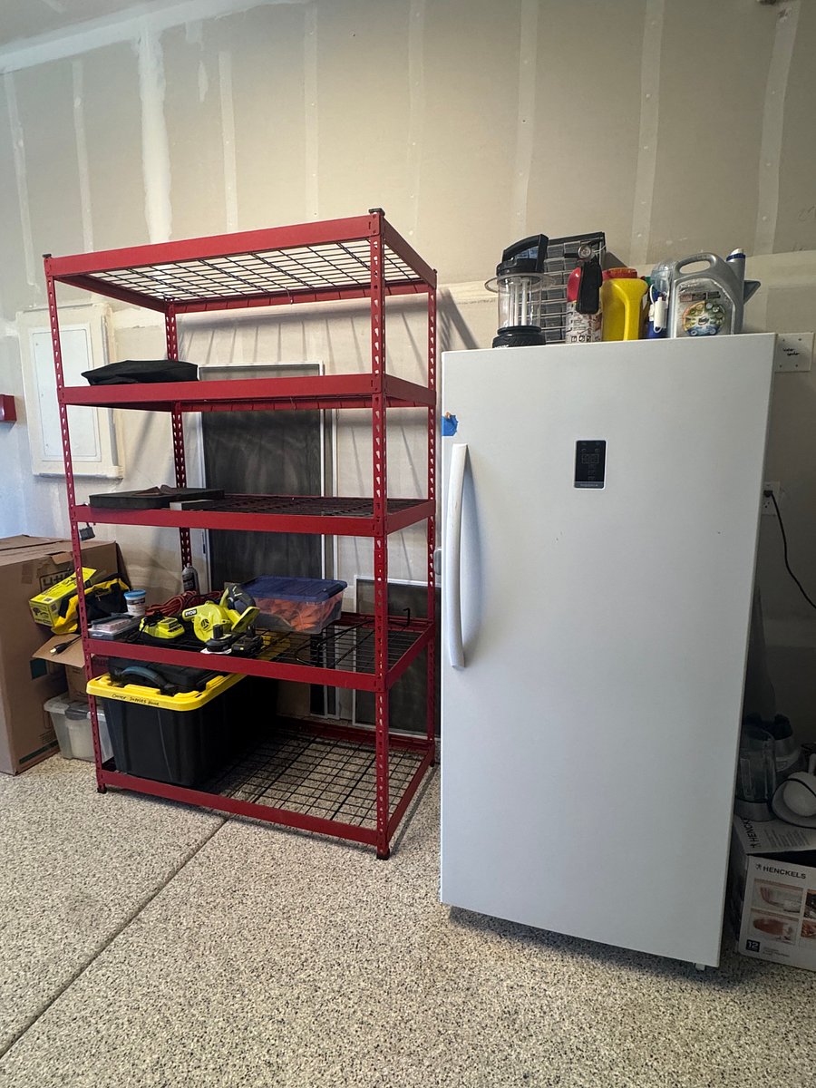 Storage racks in the garage w/ a fridge/freezer combo.
