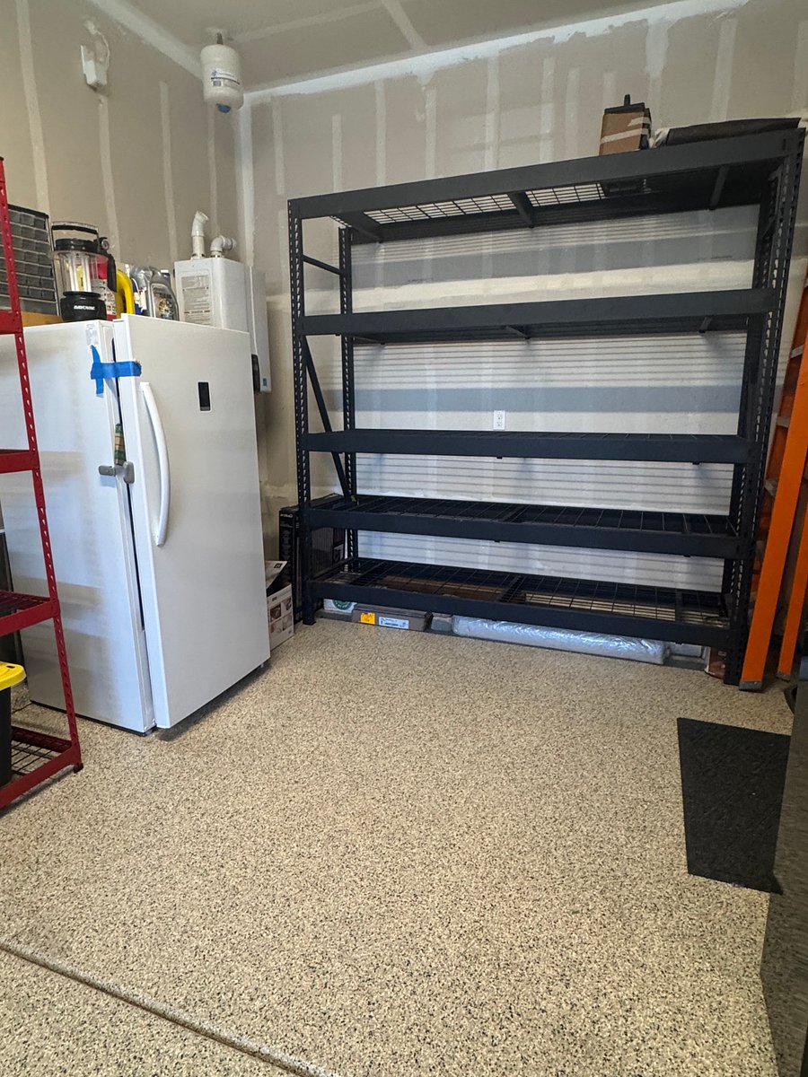 Storage racks in the garage w/ a fridge/freezer combo.