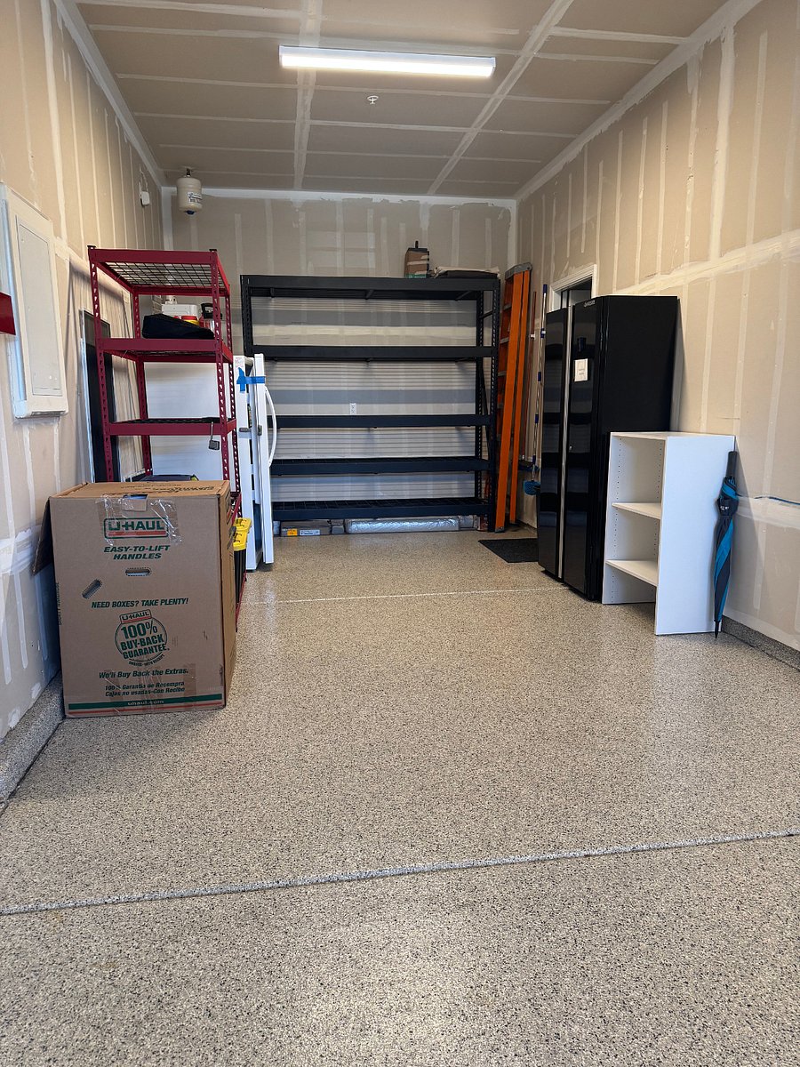 Storage racks in the garage w/ a fridge/freezer combo.
