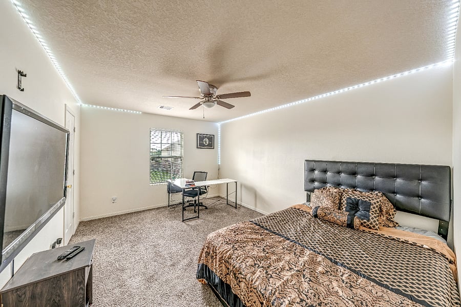 Bright and inviting bedroom featuring a Smart TV, comfortable furnishings, and convenient storage.