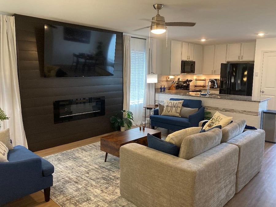 The living room has a feature wall with an electric fireplace and a 75' 4K smart TV.