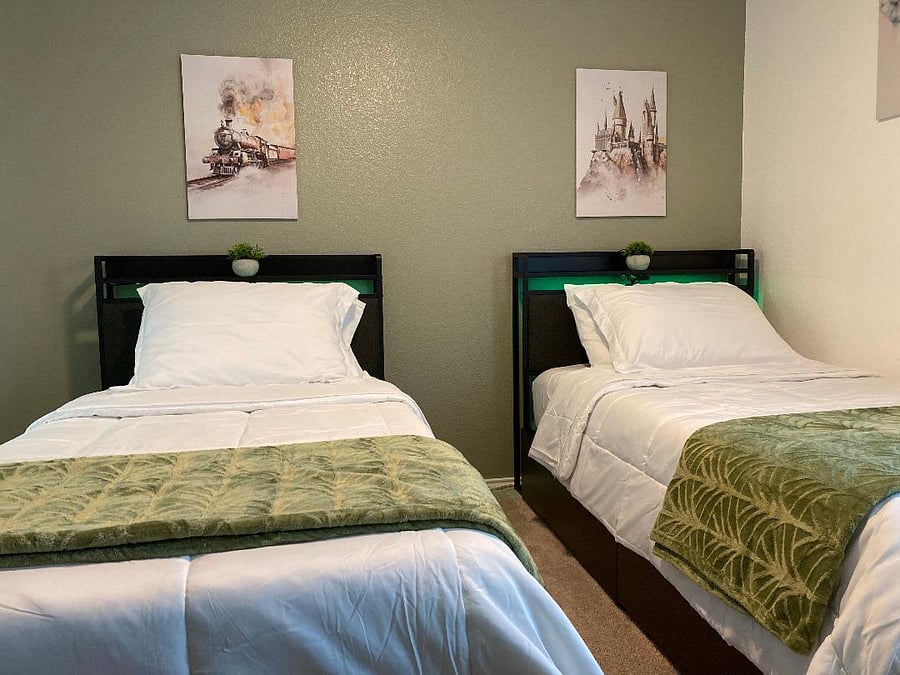 Harry Potter themed guest room for kids with a 65" 4K UHD Roku TV, games, full length lighted mirror and two twin beds.