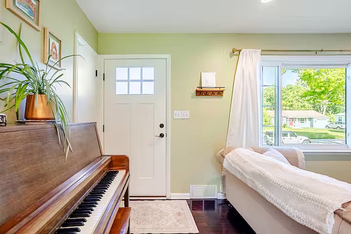 Bright and inviting living room with comfortable seating, natural light, and a piano that adds a warm, welcoming touch to the space.