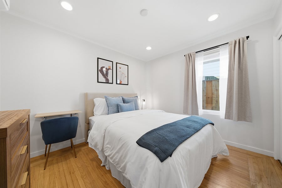 Fully furnished bedroom with queen-size bed, nightstand, dresser, closet, and a dedicated desk and chair for working or studying