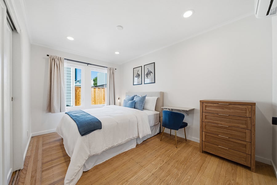 Fully furnished second bedroom with queen-size bed, nightstand, dresser, closet, and a dedicated desk and chair for working or studying