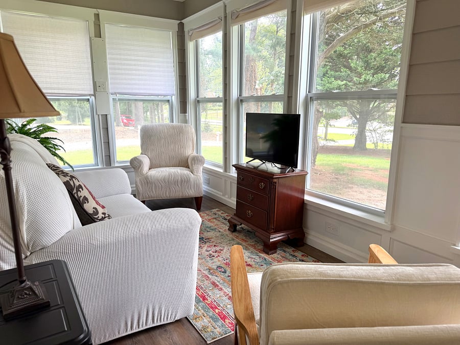 Sunny sitting room is filled with comfortable chairs and a second smart TV.