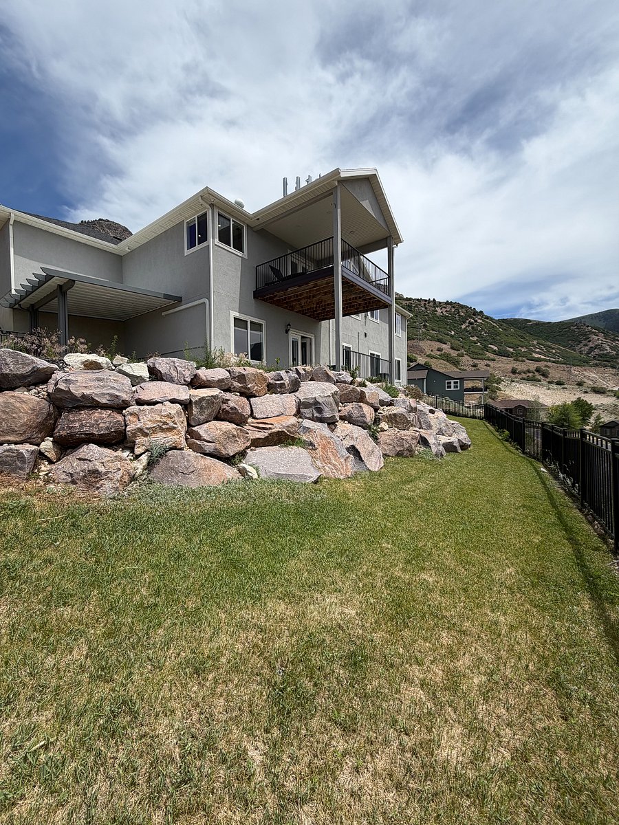 Backyard with covered deck, patio access and terraced rock landscaping.