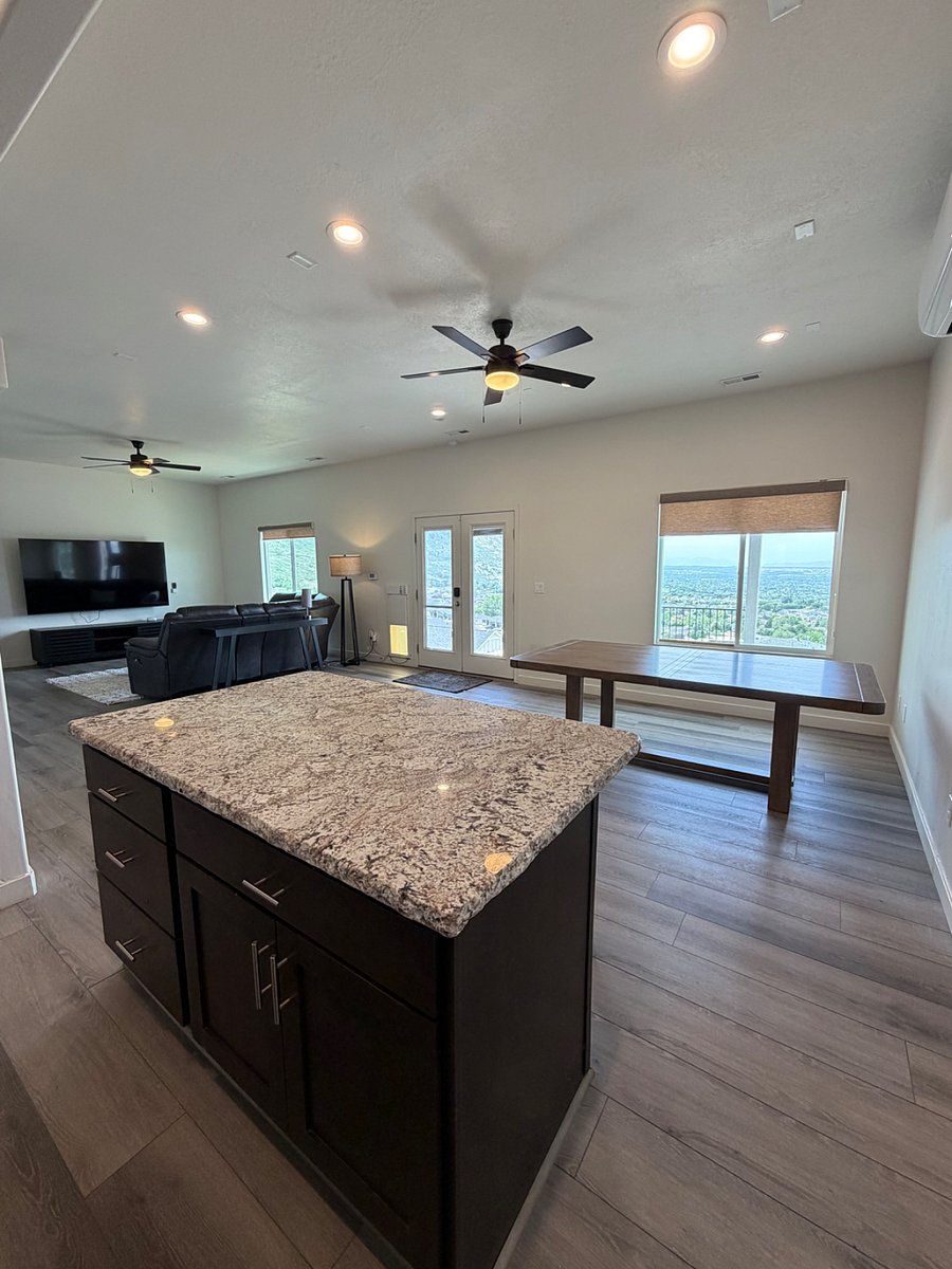 Expansive lower-level family room with large sectional seating, smart TV, and atrium doors leading to a patio and sweeping panoramic views.