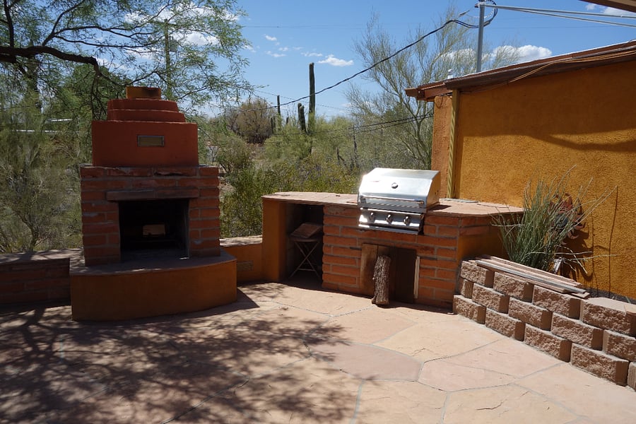 Side patio with outdoor fireplace and gas grill