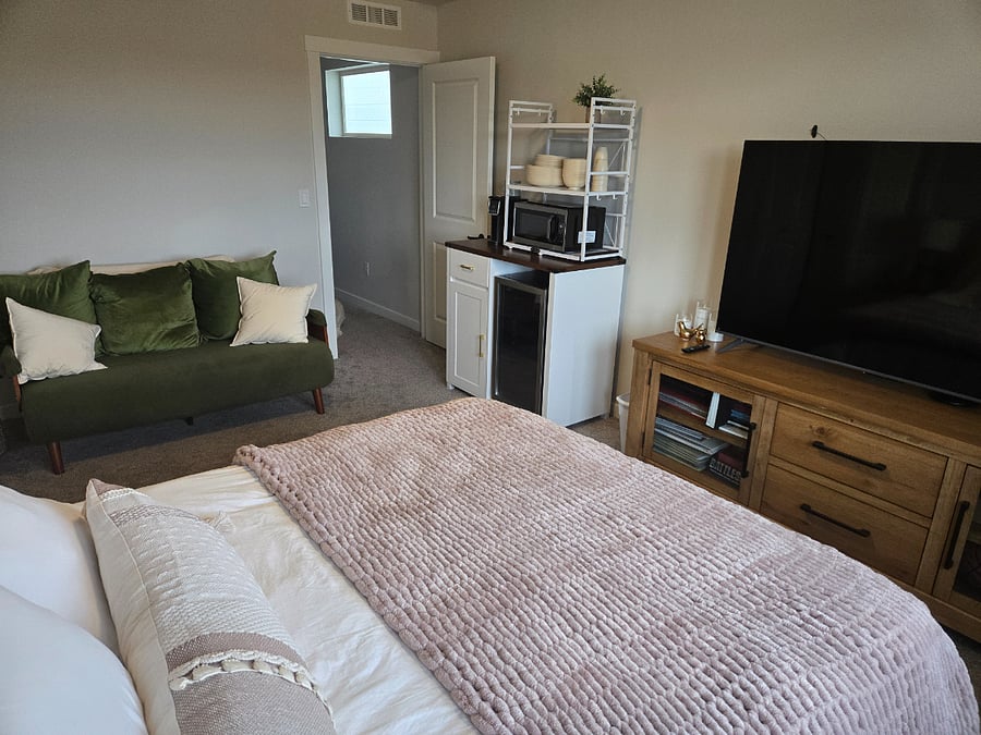 Room includes a sleeper sofa, 60-inch smart TV, small refrigerator, coffee maker and microwave.