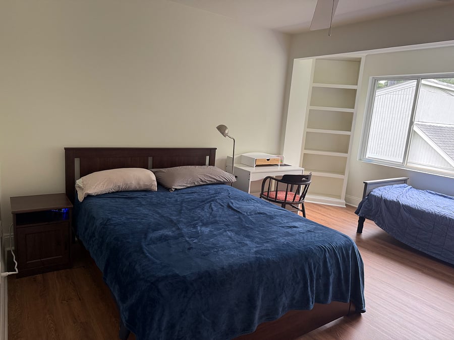 Bedside table and desk area next to queen sized bed.