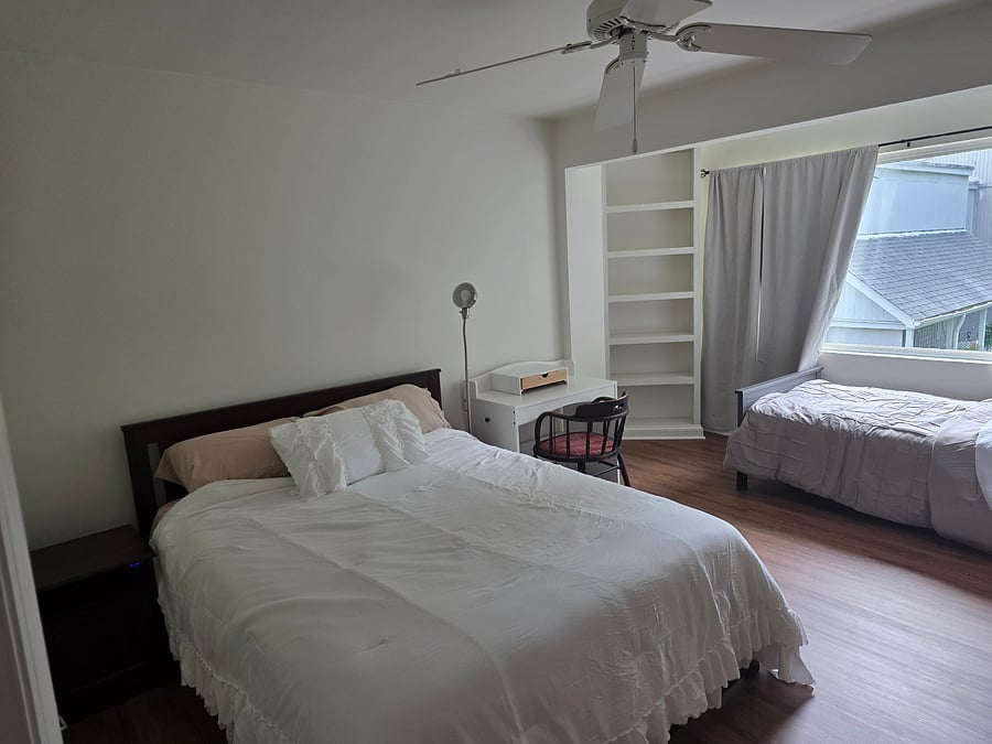 Bedside table and desk area next to queen sized bed. Twin bed also set up in primary bedroom, if needed. Please also note lots of natural light.