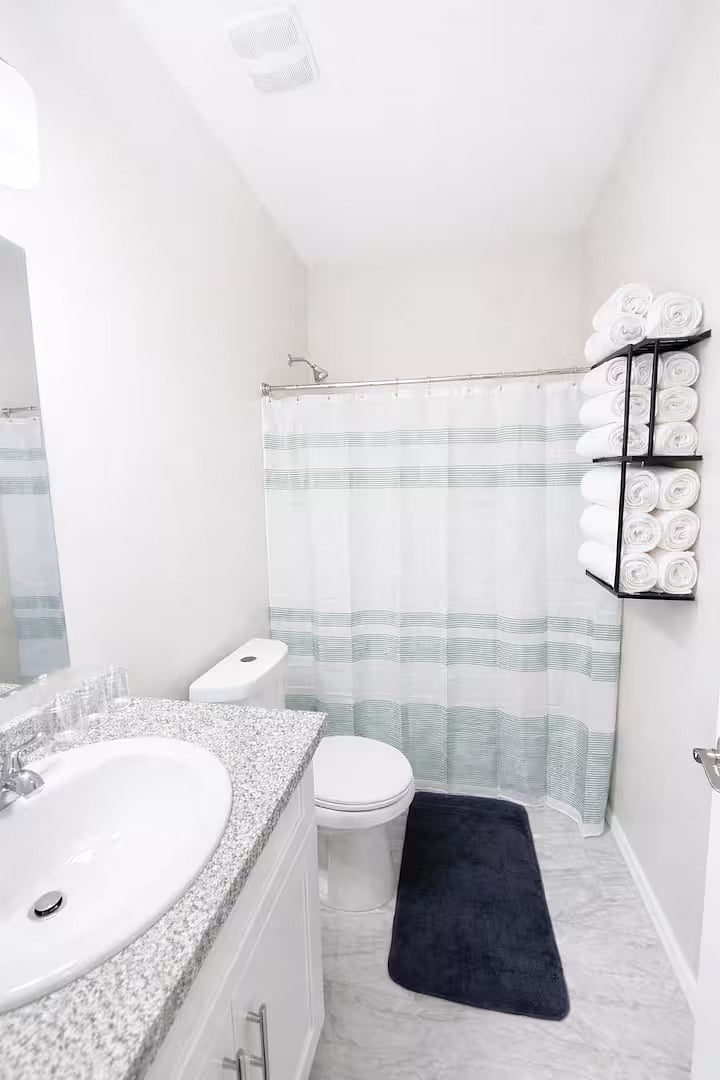 Clean and modern bathroom with a full shower, fresh towels, and bright lighting everything you need for a comfortable and refreshing stay.
