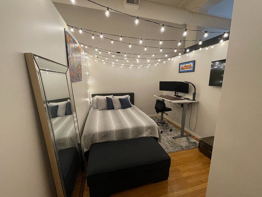 Guest bedroom featuring a docking station (compatible with PCs), 2 Lenovo 24" monitors, an adjustable standing desk, and mounted 45" Samsung Smart TV.
