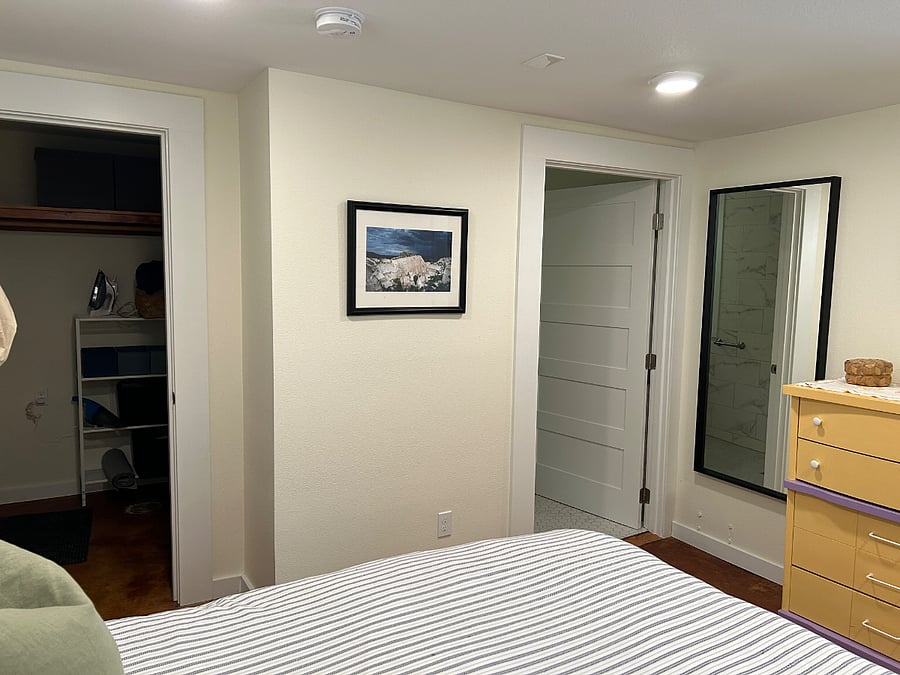 The bedroom includes a large closet/storage area. The bathroom located through the door next to the dresser and full-sized mirror.
