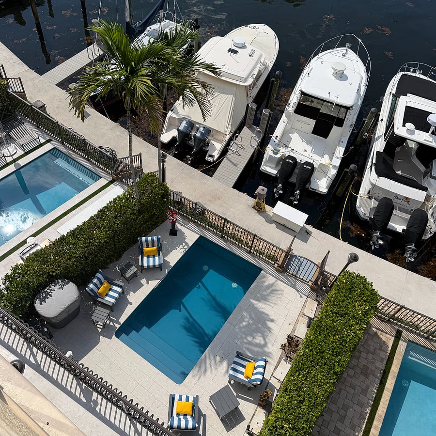 My pool with the blue and white striped cushions out and the boat slip steps away, directly beyond it