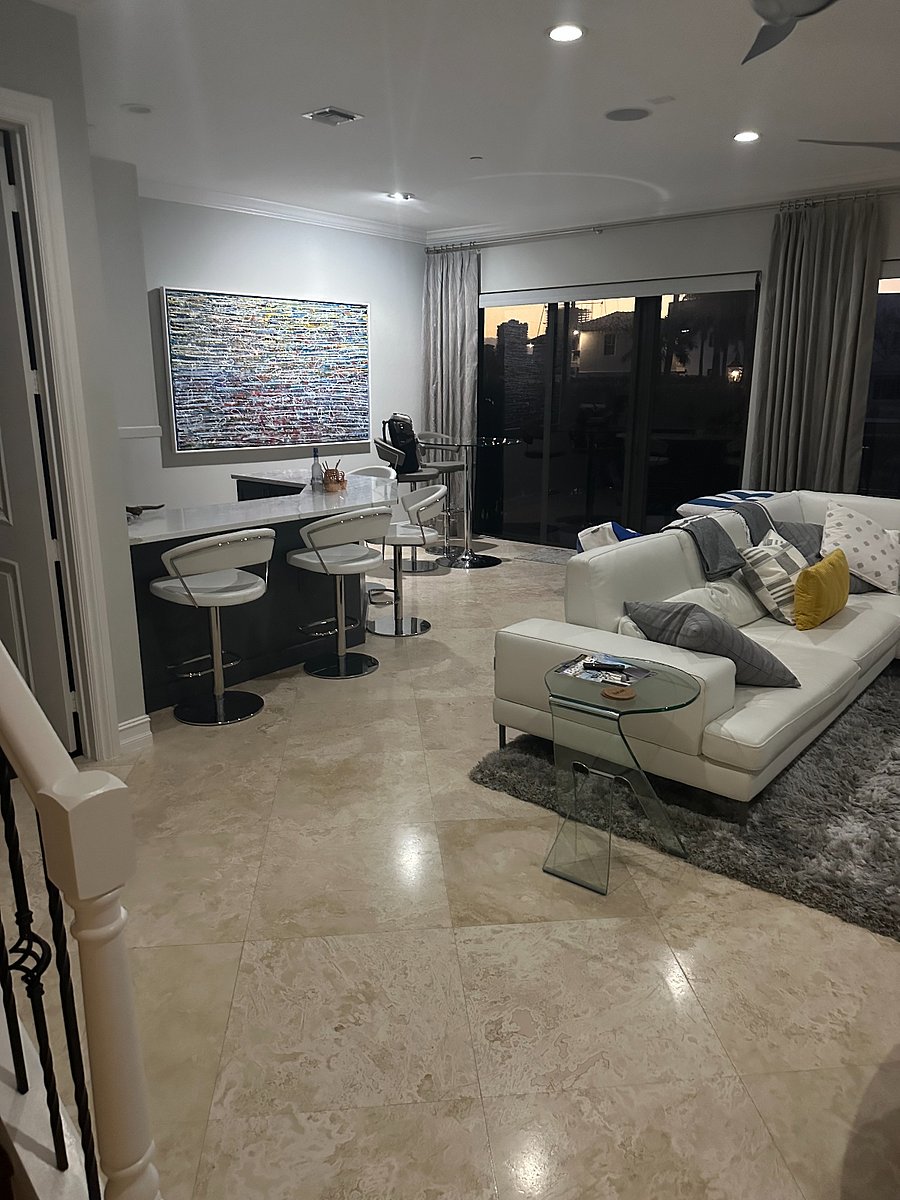 First floor living area with smart TV, large expandable leather sectional couch, bar, and access to pool deck (at left is door to office)