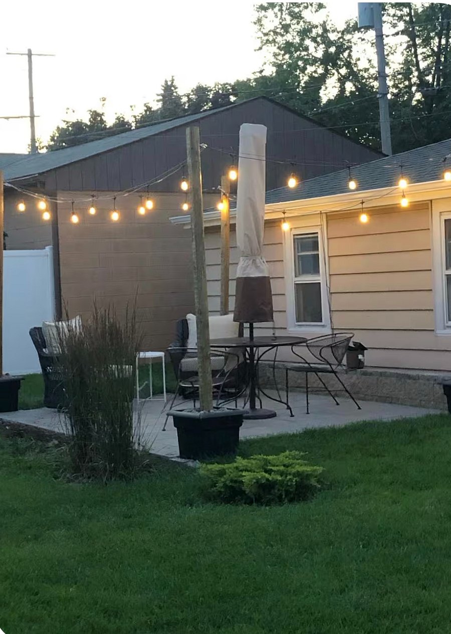 Patio with two oversized chairs, outdoor dining table, grill, and umbrella.
